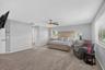 Spacious room featuring neutral carpeting, a central ceiling fan with integrated lighting, and horizontal blinds on the windows