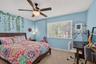 Neutral carpeted flooring, large window with horizontal blinds, and ceiling fan with integrated lighting