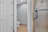 Walk-in shower with a glass door, rainfall showerhead, and tile surround featuring a decorative mosaic accent band, accompanied by tile flooring and w