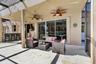 Covered outdoor living area featuring a concrete patio, stone-veneer wet bar, dual ceiling fans, and sliding glass entry doors