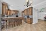 Kitchen featuring custom raised-panel wood cabinetry, stone countertops, integrated beverage refrigerator, recessed lighting, and a multi-arm chandeli