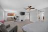 Spacious room featuring neutral carpeting, a central ceiling fan with an integrated crystal-style light fixture, and white interior doors