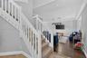 Staircase featuring white balusters and handrail, neutral-tone carpeting, wood-finish flooring, and crown molding