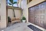 Stucco exterior entrance featuring a double-door entry with raised panel detailing, concrete paver flooring, and a tiled roofline