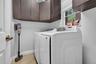 Laundry space featuring dark-finish built-in cabinetry, light wood-finish flooring, and a multi-pane window