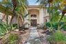 Stucco exterior featuring an arched entryway, double wood doors, arched transom window, and a tile roof