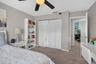Bedroom featuring wall-to-wall carpeting, ceiling fan with integrated lighting, built-in shelving, and white louvered-style closet doors