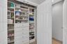 Linen closet featuring white built-in shelving, integrated drawers with metallic hardware, and double-door entry