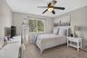 Neutral-toned room featuring wall-to-wall carpeting, a multi-blade ceiling fan with an integrated light fixture, and a window with a curtain rod