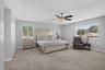 Neutral-toned interior featuring carpeting, dual windows, and a multi-blade ceiling fan with an integrated light fixture