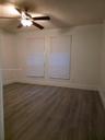 Interior space featuring wood-finish flooring, neutral wall paint, and a ceiling fan with integrated lighting, complemented by dual windows with insta