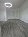Interior space featuring wood-finish flooring, a contemporary circular LED chandelier, three bay windows, and neutral wall tones