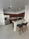 Kitchen featuring stained wood cabinetry, stone-finish countertops, stainless steel refrigerator, recessed lighting, and a breakfast bar