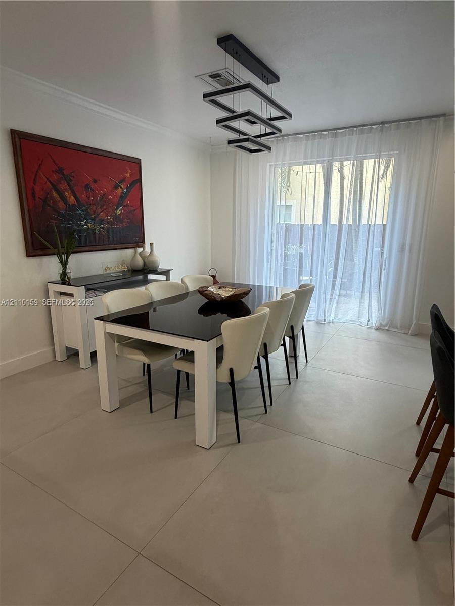 Large-format tile flooring, multi-tiered geometric pendant lighting, and sliding glass doors featuring floor-to-ceiling sheer drapery