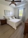 Tray ceiling with a central ceiling fan and wood-finish flooring