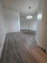 Neutral interior space featuring wood-finish flooring, a contemporary circular pendant light fixture, and a built-in closet with sliding doors