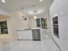 Modern kitchen featuring high-gloss white cabinetry, a center island with a stone-finish countertop, stainless steel double wall ovens, a stainless st