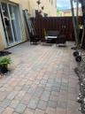 Private rear patio featuring concrete paver flooring, full-height privacy wood fencing, and sliding glass door access