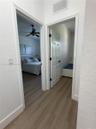 Interior hallway featuring wood-finish flooring, white door casings, and paneled doors with matte black hardware