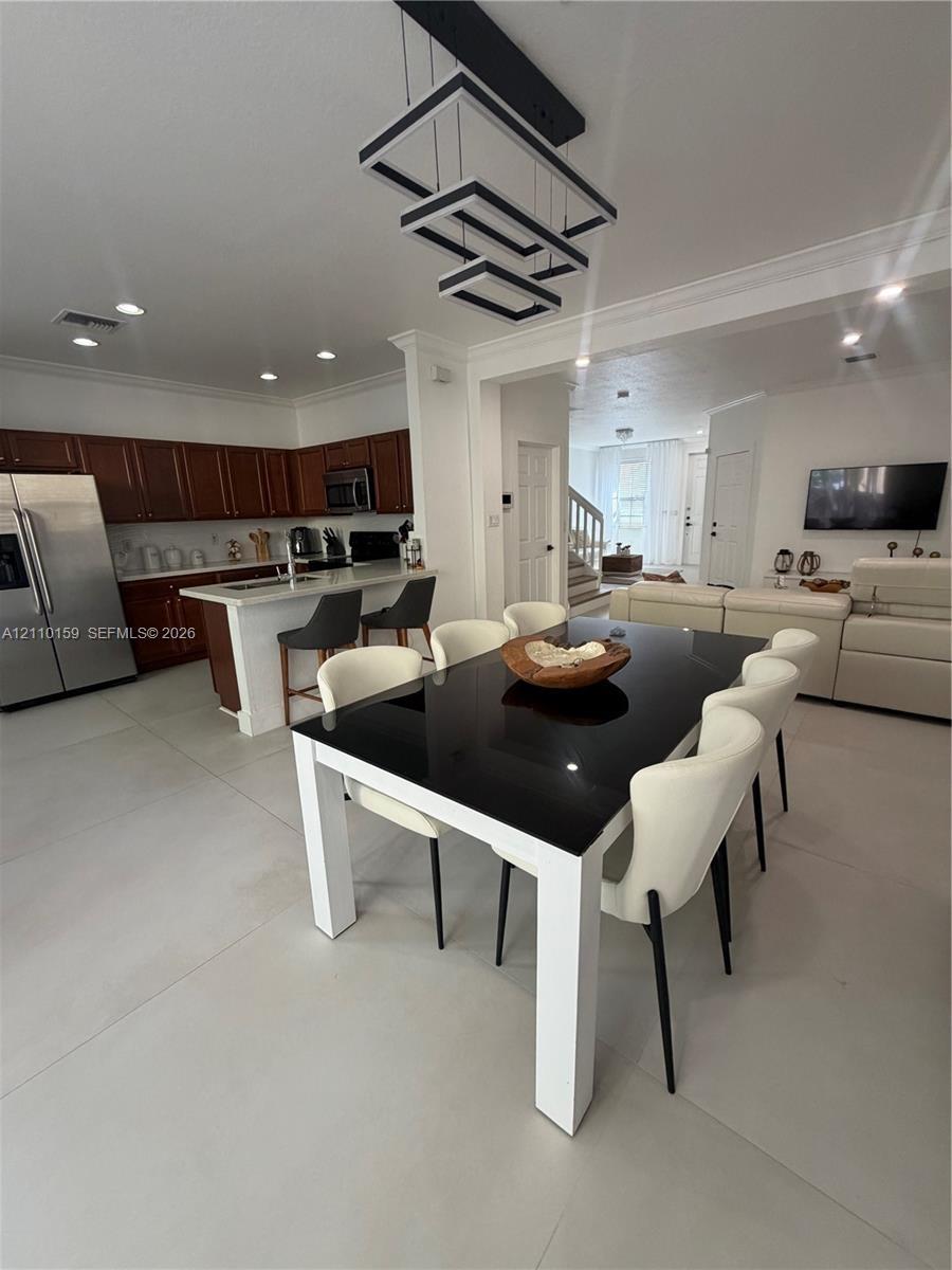 Open-concept kitchen featuring dark wood cabinetry, an expansive island with a white countertop, large-format tile flooring, recessed lighting, and a 