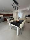 Open-concept kitchen featuring dark wood cabinetry, an expansive island with a white countertop, large-format tile flooring, recessed lighting, and a 