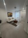 Large-format porcelain tile flooring, recessed lighting, crystal-style flush mount ceiling fixture, and a six-panel entry door