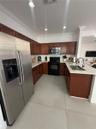 Kitchen featuring wood cabinetry, stone-finish countertops, large-format tile flooring, stainless steel side-by-side refrigerator, and built-in microw