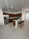 Kitchen featuring dark-toned cabinetry, light-colored countertops, stainless steel appliances, a peninsula with an undermount sink, and recessed light