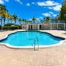 In-ground swimming pool with stone-tiled deck, metal handrails, and upper-level terrace with metal railing