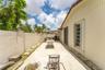Side patio featuring a concrete surface, enclosed by a solid masonry privacy wall, and partially shaded by a permanent metal awning
