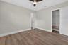 Neutral-toned interior space featuring wood-finish flooring, a ceiling fan with integrated lighting, and a closet with built-in wire shelving