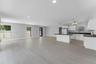 Open-concept kitchen featuring white shaker-style cabinetry, dark stone countertops, a center island, recessed lighting, and light-tone wood-finish fl