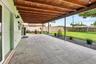 Covered outdoor patio featuring a wood-plank ceiling, large-format tile flooring, and perimeter gravel hardscaping, overlooking a fenced backyard with