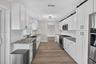 Kitchen featuring white shaker-style cabinetry, stone-patterned countertops, white subway tile backsplash, stainless steel appliances, and wood-finish