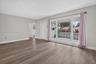 Living area featuring wood-finish flooring, neutral wall paint, and a large multi-pane window with a decorative concrete screen wall exterior