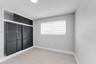 Interior space featuring light-toned wood-finish flooring, charcoal-colored louvered sliding closet doors with built-in overhead storage, and dual-lay