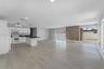 Open-concept interior featuring wood-finish flooring, a kitchen with white cabinetry and dark countertops, a natural stone accent wall, recessed light