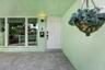 Covered entryway featuring large-format tile flooring, a six-panel exterior door, built-in wall-mounted mailbox, and oversized picture windows