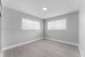 Neutral-toned interior featuring wood-finish flooring, light grey walls, recessed ceiling lighting, and windows equipped with dual-layered roller shad
