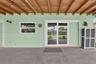 Covered patio featuring an exposed wood-beam ceiling, large-format tile flooring, and white-framed sliding glass doors