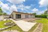 Exterior backyard featuring a concrete patio, stone-bordered fire pit, multi-level terrace, and covered side patio area