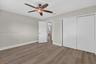 Wood-finish flooring, ceiling fan with integrated light fixture, and dual-panel sliding closet doors