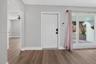 Neutral-toned interior featuring wood-finish flooring, a white six-panel entry door, and expansive glass window panes