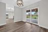 Wood-finish flooring, metal geometric chandelier, and sliding glass doors opening to a covered patio and fenced yard