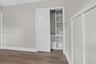 Wood-finish flooring, white board-and-batten wall detailing, and a sliding-door closet featuring built-in shelving