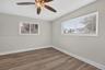 Interior space featuring wood-finish flooring, two dual-pane windows with horizontal blinds, and a multi-blade ceiling fan with integrated light fixtu