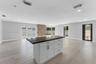 Center island featuring shaker-style cabinetry, dark stone countertop, and recessed lighting, accented by a floor-to-ceiling natural stone feature wal