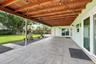 Covered patio featuring large-format stone-style tile flooring, exposed wood-beam ceiling, and sliding glass doors