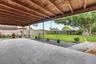 Covered patio featuring a wood-plank ceiling, large-format tile flooring, a fenced backyard, and mature landscaping