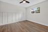 Neutral-toned room featuring wood-finish flooring, white board-and-batten wall detailing, and a central ceiling fan with integrated lighting